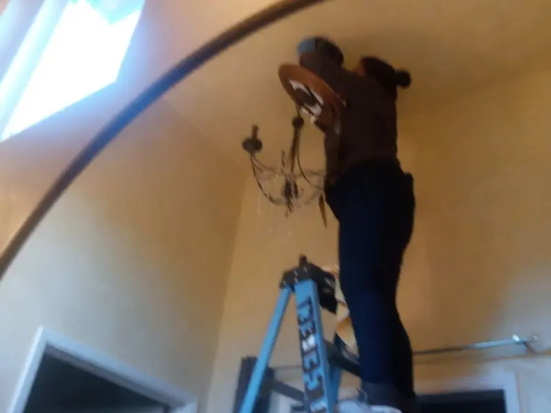 Electrician installing a chandelier in a Hutchins residence